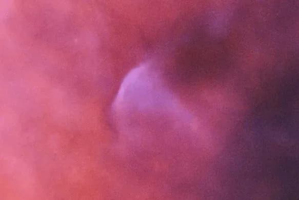 A close-up view of the bow shock in the Seagull Nebula created by the runaway star FN Canis Majoris, showing a distinct blue glowing arc of ionized oxygen.